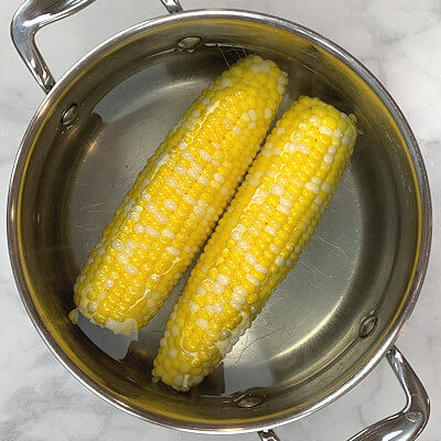 Step 1 - Bring water to a boil, add generous salt and add the corn. Cover the pot and cook the cobs for about 10 minutes. Remove the cobs from the water (reserve the water) with a slotted spoon. Once the cobs cooled down a little, grate the corn with a box grater (reserve the cobs as well).