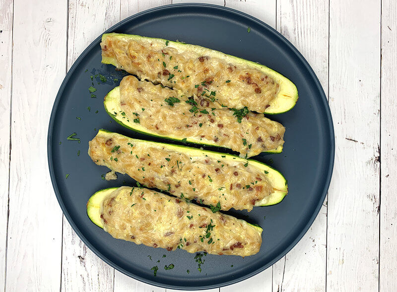 Egg-free Zucchini Orzo Carbonara served on round dark blue plate