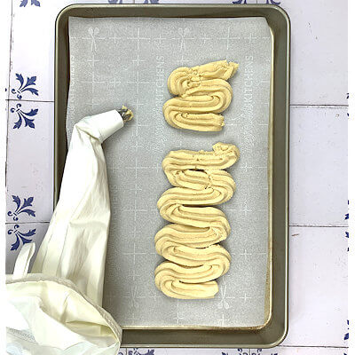 Step 3 - Transfer the dough to a piping bag with a large star nozzle and start to pipe a wave pattern on a parchment lined baking sheet. The wider the waves the bigger the cookie.