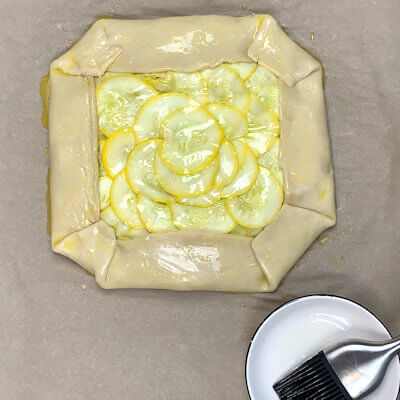Step 7 - Baste the summer squash slices with olive oil, preventing the slices to dry out during baking or burn before the pie is done.Slide the baking sheet in an oven of 400 degrees F. and bake for 30-35 minutes.