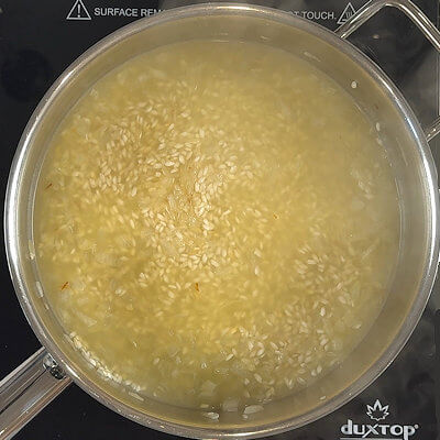 Step 4 - Add the white wine to the skillet and loosen the particles that are stuck to the bottom of your pan (this is called deglazing). Stir until the wine is fully absorbed.Add 1/4-1/2 cup of heated broth and simmer and stir until it is fully absorbed. 