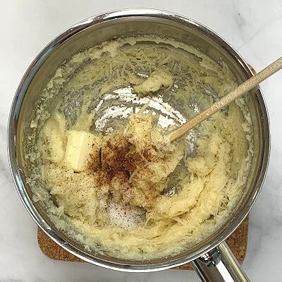 Step 2 - Add cheese, butter, salt, pepper and nutmeg and stir again.