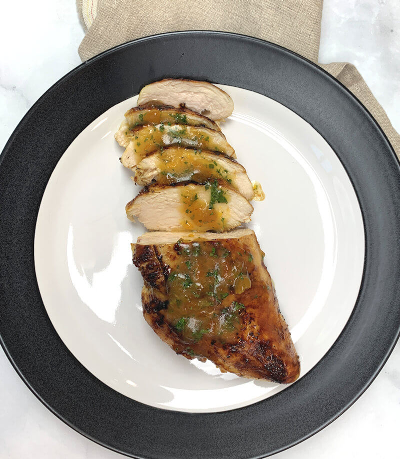Chicken with Apricot Mint Sauce on white plate with black perimeter.