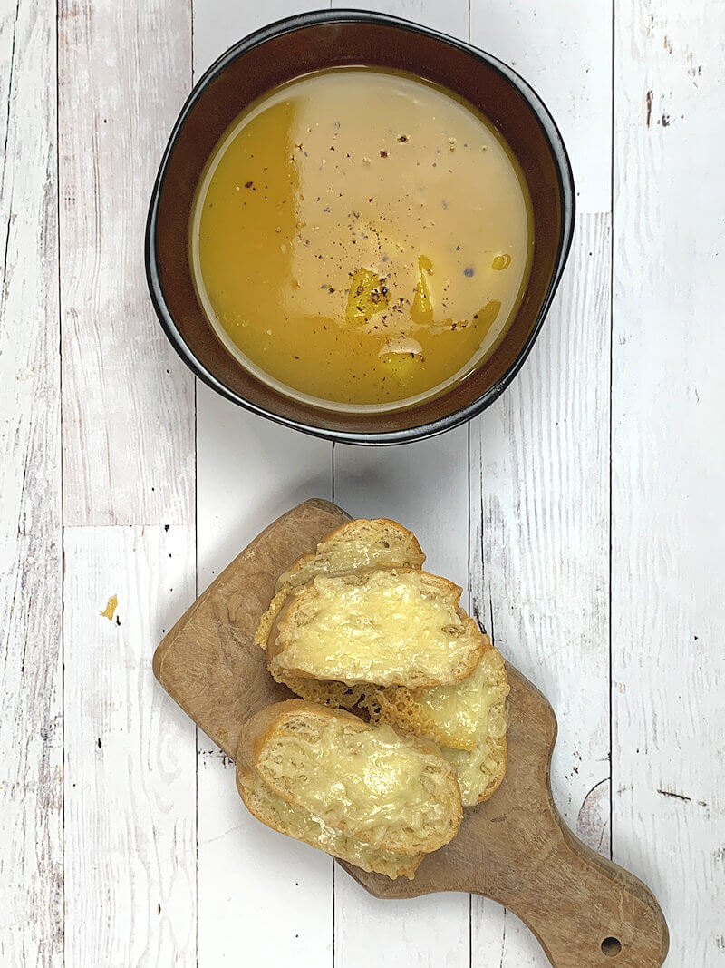 Bowl with Curried Pumpkin Soup and small wooden plank with Gruyère toast