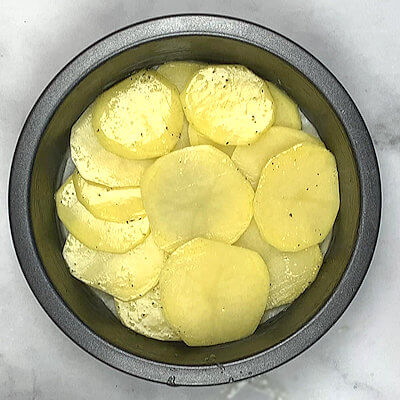 Step 3 - Arrange 2 layers of potato slices in the bottom of the pie dish.