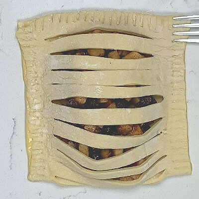 Step 5 - Fold the half with the slits over the apple filling. Press down on the border with your fingers and solidify that by using a fork. 