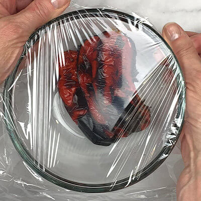 Step 2 - Place the pepper halves in a bowl and seal with plastic wrap or place a fitting plate on top. Let sit for at least 20 minutes. They will sweat in the airtight space and the skin will start to loosen.