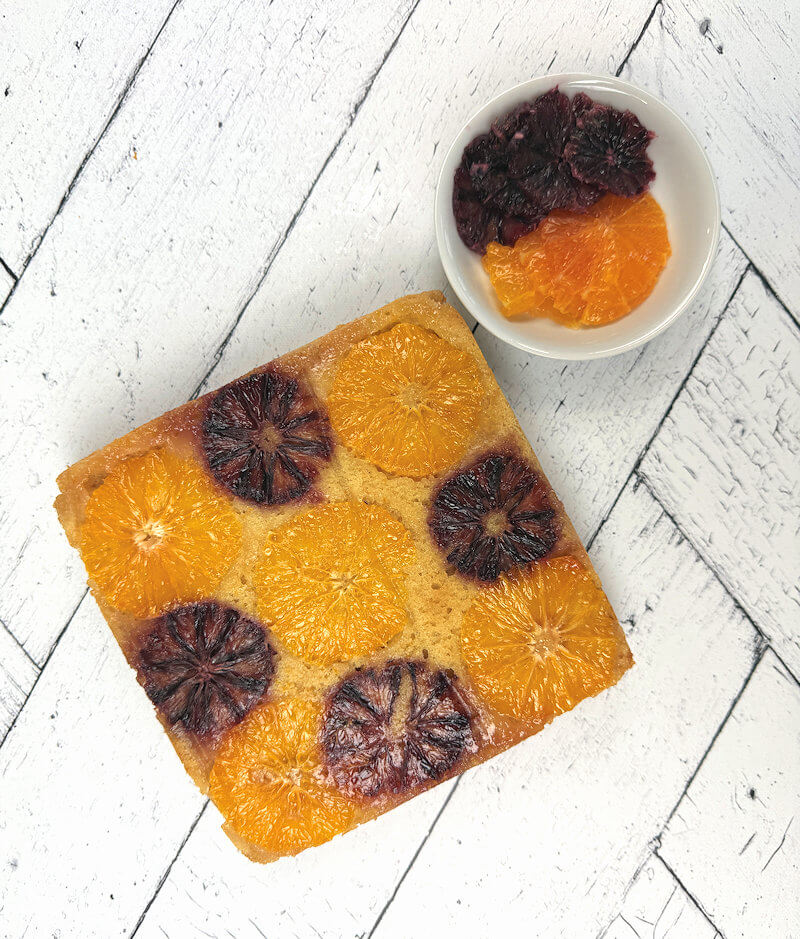 Entire Orange Almond cake with small dish with slices of oranges