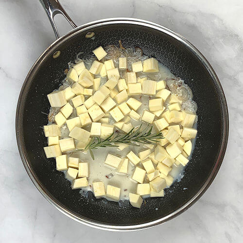 Add milk, stock and parsnip cubes to same skillet as well as rosemary.
