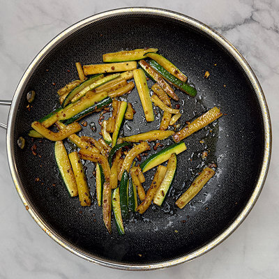Step 2 - Heat oil in a skillet and saute minced garlic and zucchini, which you cut as short sticks. Cook until browning and zucchini is softening. Season with salt & pepper. 