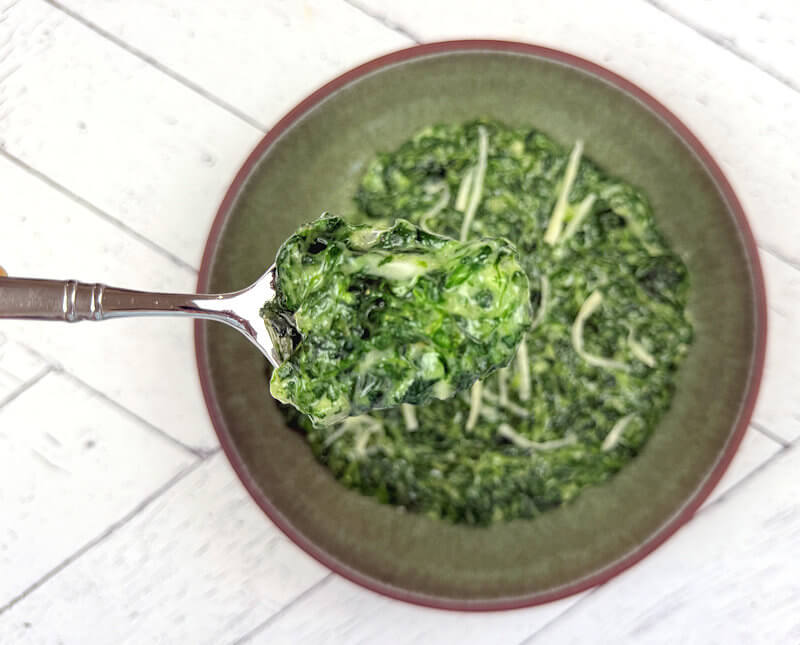 Close-up of creamed spinach on spoon.