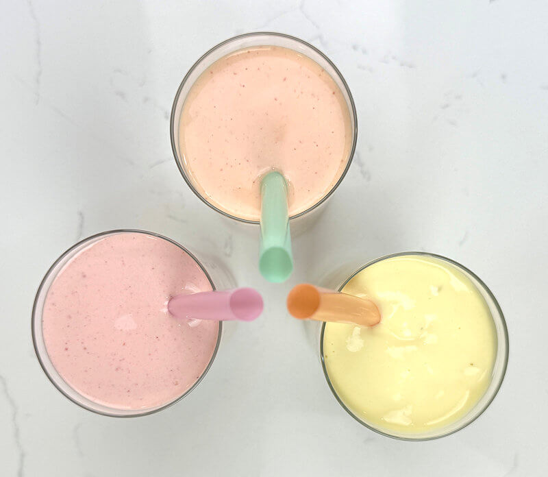 Top down view of 3 smoothies in glasses with wide straw.