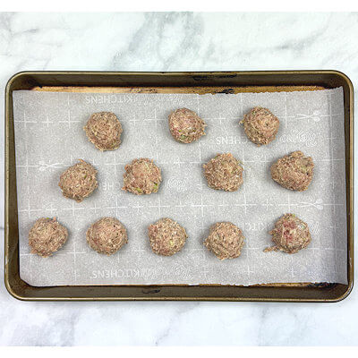 Step 2 - Line a sheet pan with parchment paper. Using a 2 1/4" cookie scoop and roll into meatball.