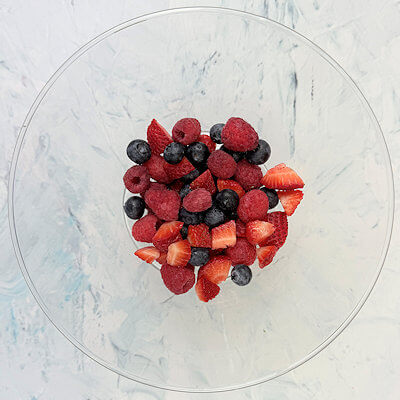 Step 2 - Cut the large strawberries in smaller pieces and mix them with the blueberries and raspberries. Top the granola with half of the mixed berries.