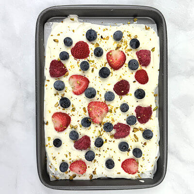 Step 3 - Scatter slices strawberry, blueberries and raspberries as well as chopped pistachios on top of the yogurt. Place the baking sheet in the freezer for at least 3 hours or until yogurt is firm.