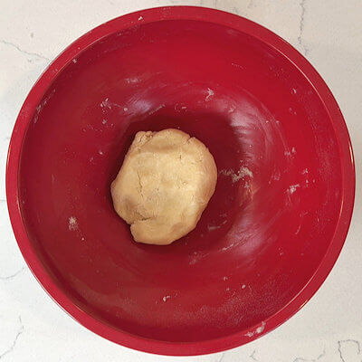 Step 2 - Add the ice water, a tablespoon at a time, until the mixture just comes together. Wrap the crumbly dough ball in plastic wrap and flatting into a small disc. Refrigerate for at least 1 hour. While the dough is resting, wash the plums, cut them in half, remove the pit and slice them thinly 