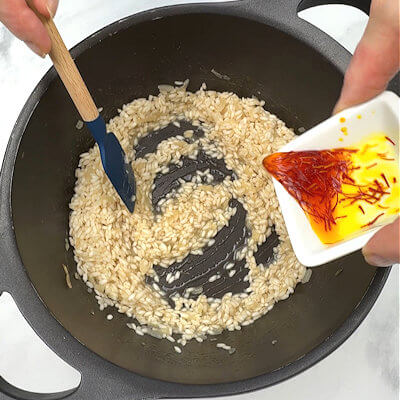 Step 3 - Add the soaked saffron with the stock about half way through the cooking process of the risotto. Risotto takes about 15-20 minutes to cook, so just before 10 minutes, add the saffron. Continue adding stock in increments and you’ll see the rice turn beautifully yellow.