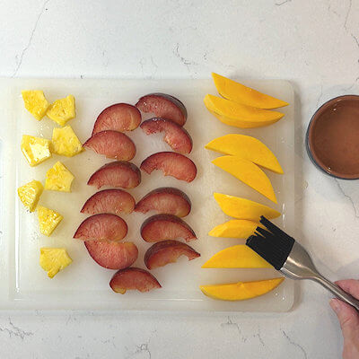 Step 1 - Peel the pineapple and cut in chunks. Peel the mango and cut in wedges. Cut the plums in wedges (no need to peel them). Brush all the sides of the fruit with olive oil.