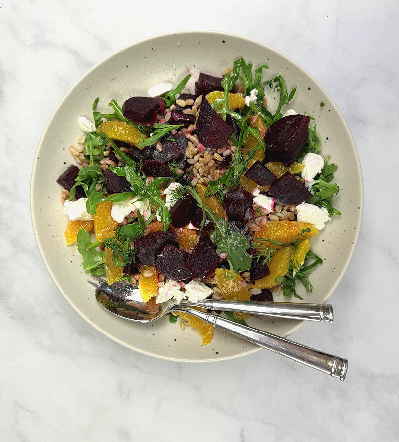 Bowl with beet, orange & farro salad. Serve with spoon and fork.