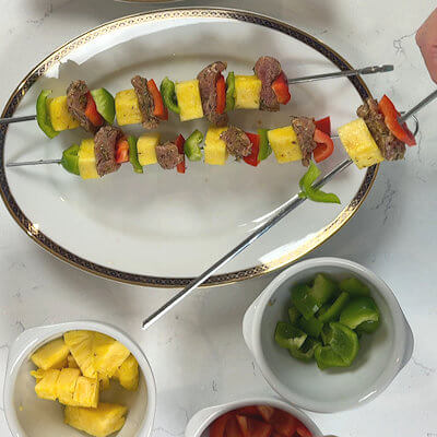 Step 2 - Transfer the pork cubes onto paper towels and allow most of the marinade to be absorbed. Thread the red bell pepper, pork tenderloin, pineapple and green bell pepper onto the skewers. 