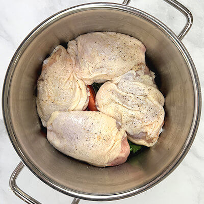 Step 2 - Place the chicken thighs that, are seasoned with salt and pepper, on top of the vegetables. Cover the chicken with water so they are just submerged.