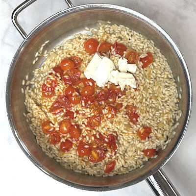 Step 3 - Add to burst tomatoes and the goat cheese to the risotto  and mix. Allow the cheese to melt. 