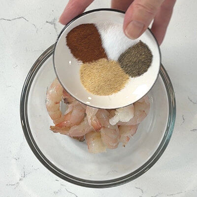 Step 4 - Peel and devein the shrimps, but leave the tail on. This looks nicer than without the tail. Season the shrimps with garlic powder, chili powder and salt & pepper.