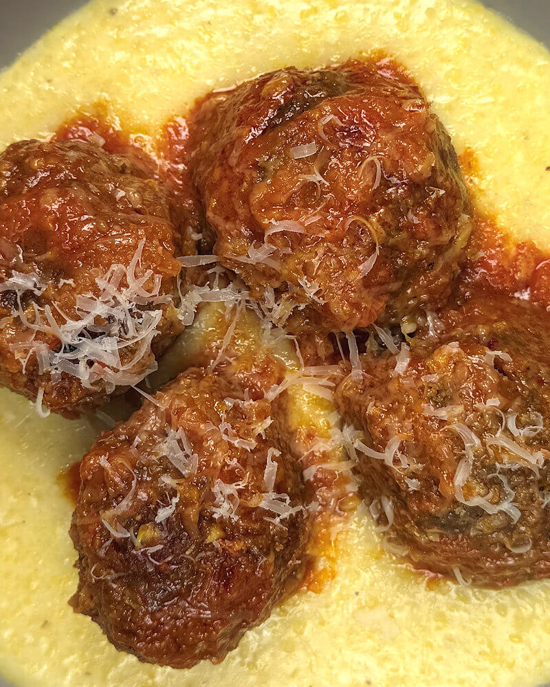 Zoomed in image of Italian meatballs on polenta.