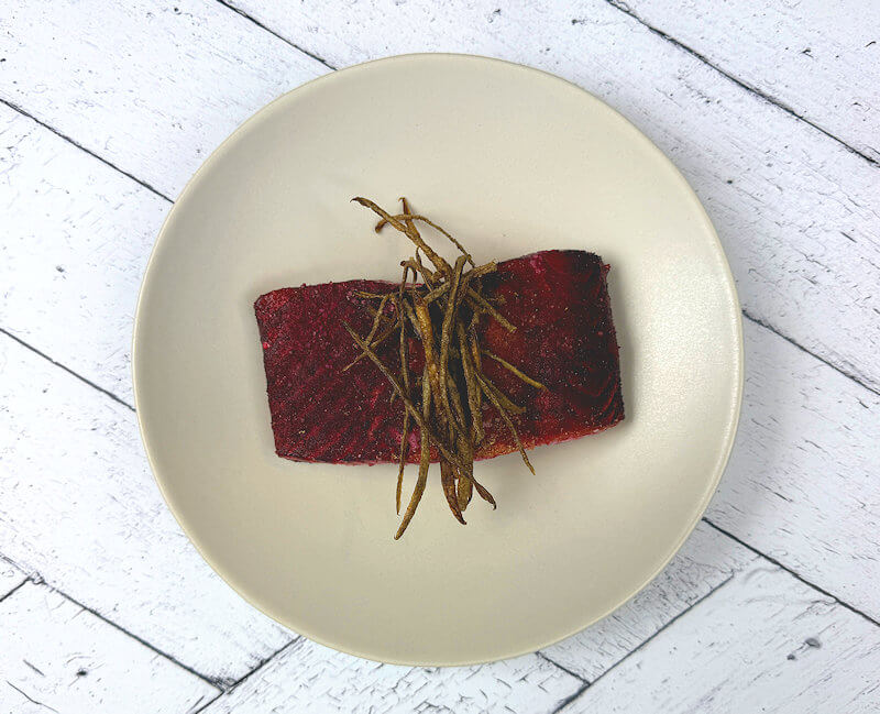Transfer the beet marinated grilled salmon onto a plate and garnish with the potato strips.