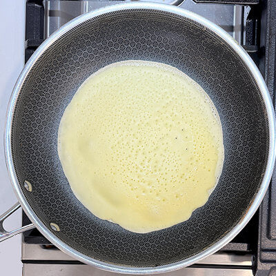 Step 3 - Heat a 10-inch nonstick skillet over medium heat and brush with butter. If the batter has thickened too much, add a little bit of milk. Ladle 1/4 cup of batter into the pan, turning and tilting the skillet to coat the bottom. Cook until the top of the crêpe is set and the bottom is golden brown. Turn with a spatula and cook the other side in less than 1 minute.