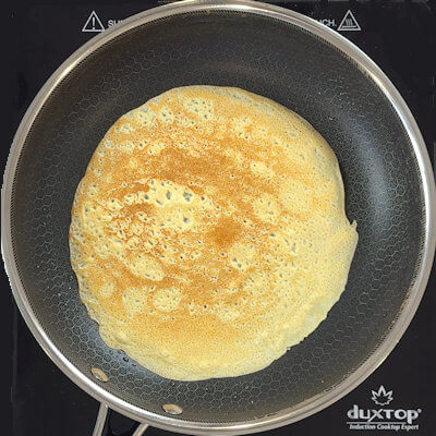 Step 3 - Heat a 10-inch nonstick skillet over medium heat and brush with neutral oil or butter. Ladle 1/4 cup of batter into the pan, turning and tilting the skillet to coat the bottom. Cook until the top of the crêpe is set and the bottom is golden brown. Turn with a spatula and cook the other side in less than 1 minute.