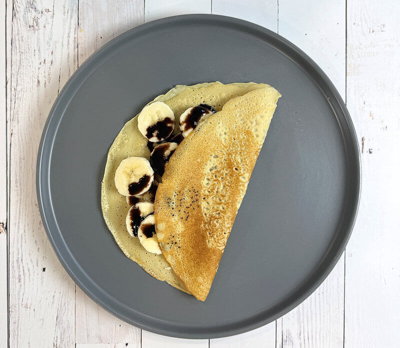 A quinoa breakfast crepe variety with banana and chocolate sauce.