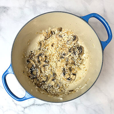 Step 4 - Add the rice and roast it by stirring it until you see white spots on the grains. Deglaze (adding liquid into a pan in order to loosen the particles that are stuck to the bottom of your pan) the pan with white wine and stir until the wine is fully absorbed.