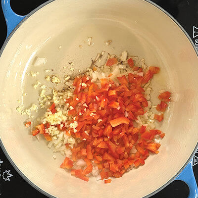 Step 2 - Heat oil in a Dutch oven and add onion, red bell pepper and garlic until translucent and softened.