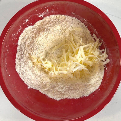 Step 2 - Cut the ice cold butter in small pieces. You can do this with a box grater, a pastry blender, a food processor or two knives. Add the grated butter to the flour mixture and stir, so the flour coats the butter.
