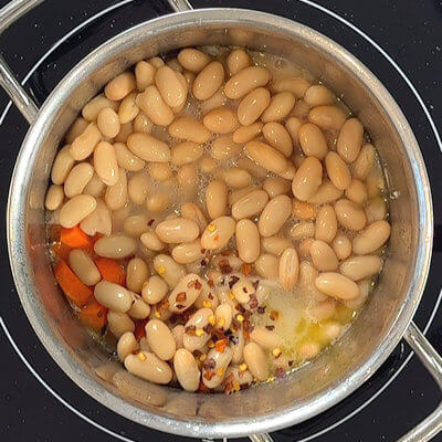Step 2 - Add carrots, cannellini beans and crushed red peppers and simmer for about 5 minutes.
