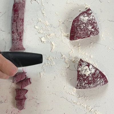 Step 4 - Unwrap the dough and cut it in 4 or more pieces. Roll each piece into a long tube. Cut that tube in pieces of about 1 inch. These are you raw gnocchi.At the same time, bring a pot of water with salt to a boil.