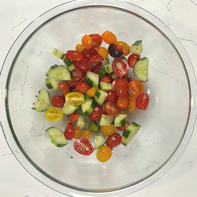 Step 4 - Wash and peel the cucumber. You can peel the cucumber entirely or peel alternating strips of the skin. I like the latter as that is an visually attractive. Cut the tomatoes in half. Add the red wine vinegar, season with salt & pepper and gently toss.