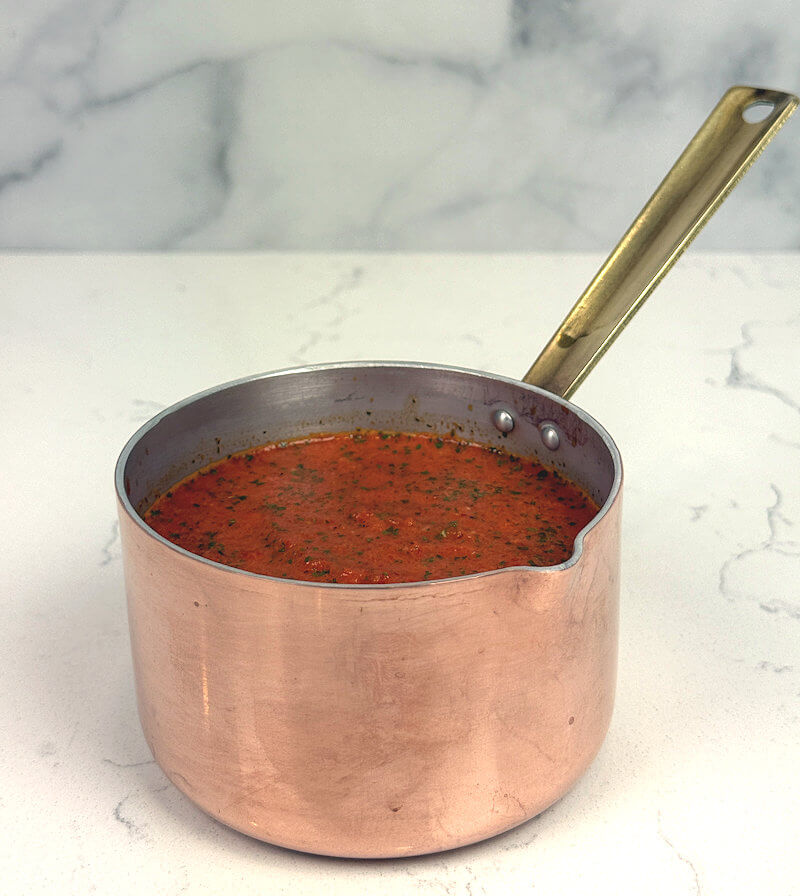Side look of tiny copper pan with roasted red pepper sauce