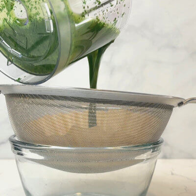 Step 4 - This step is optional. Pour the basil oil through a fine mesh strainer or sieve or if you want it even cleaner, use a coffee filter or a cheese cloth. Gently press with a spoon to get all the oil out of the mixture. 