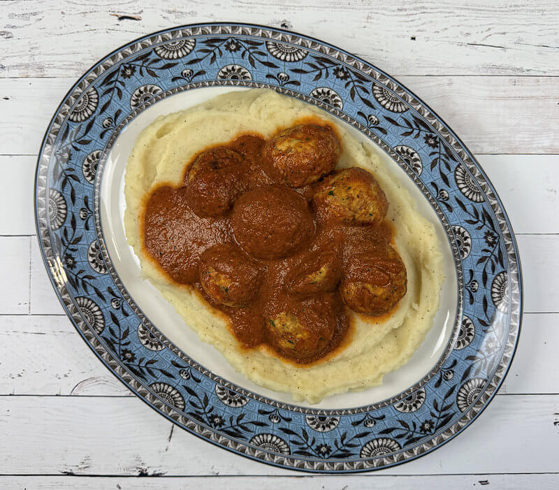 Chicken Meatballs with Red Pepper Sauce served on a bed of mashed potatoes.