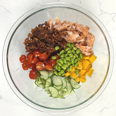 Step 5 - Was and chop the sale ingredients: mango, cucumber and tomatoes and transfer to a large bowl. Add the crispy rice and salmon as well. Toss the salad with the dressing until it is fully coated.