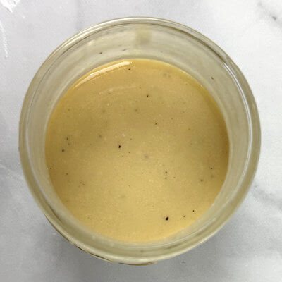 Step 3 - Make the dressing by transfering all ingredients, except the olive oil, to a bowl or tall sturdy glass. With an immersion blender mix until you have a unified mixture and the salt is dissolved and spices well mixed. Then slowly add the olive oil while the immersion blender is running.