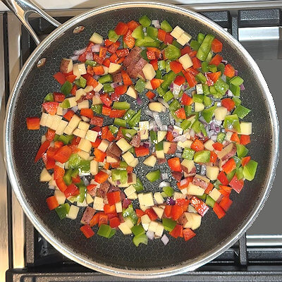 Step 1 - Heat oil in a skillet and add onion, potato, bell peppers (all chopped to equally sized pieces) and salt. Stir.