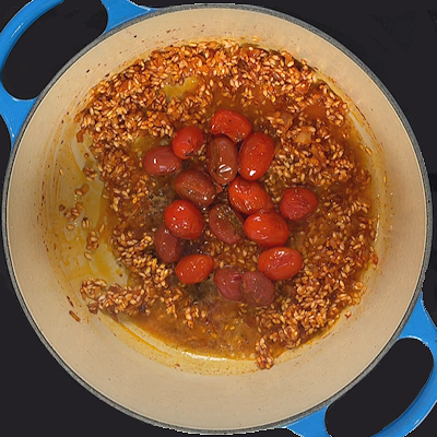 Step 5 - Add the rice and stir, so all rice grains are coated with the tomato paste and shallot and are slightly toasted. Add the tomatoes back into the pan (keep a few in reserve for garnish) as well as the white wine and cook until the wine is absorbed by the rice.