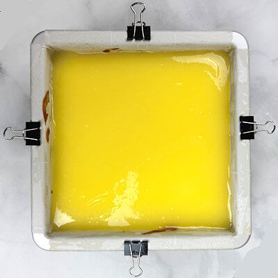 Step 6 - When the cheesecake comes out of the oven, pour all the curd onto the cheesecake and use offset spatula to spread it evenly. Cool at room temperature, then refrigerate overnight, or at least 5 hours. Refrigerate uncovered.