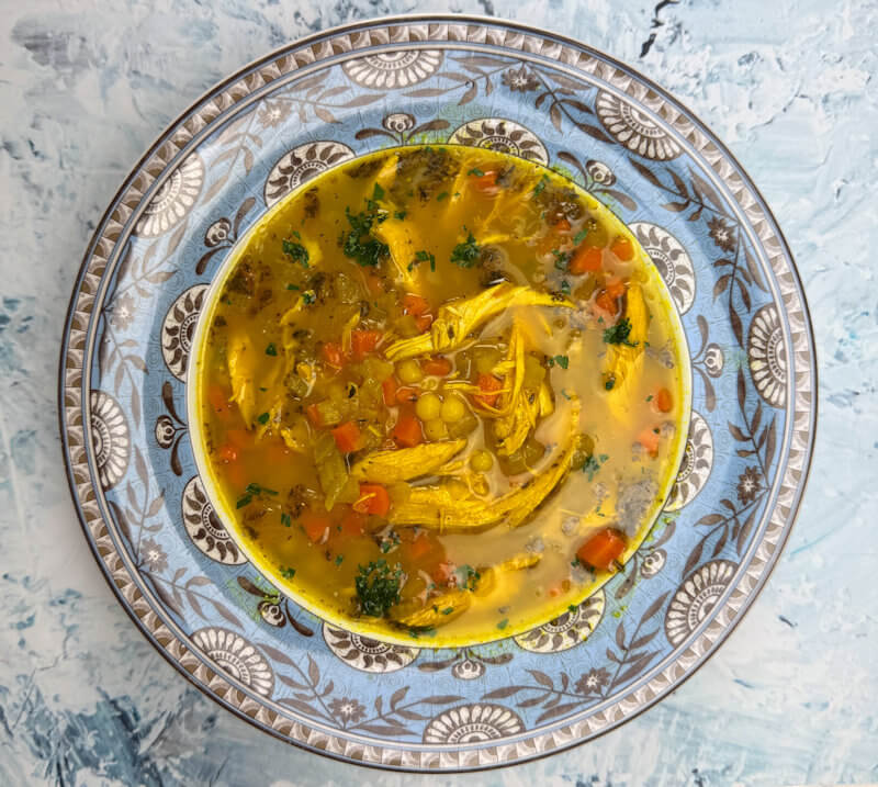 Turmeric chicken soup in a soup plate.